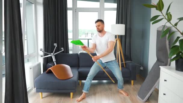 Ο άνθρωπος καθαρίζει το σπίτι και διασκεδάζει χορεύοντας με μια σκούπα. Αργή κίνηση — Αρχείο Βίντεο