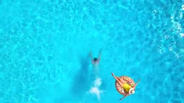 Kız donut havuzunda yüzerken adamın hava manzarası havuza dalıyor.
