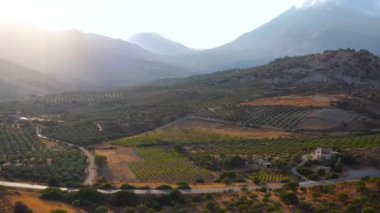 Yunanistan 'daki Girit adasının havadan görünüşü. Gün batımında dağ manzarası, zeytin ağaçları ve üzüm bağları..
