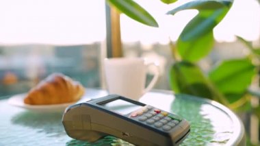 Akıllı telefondan yapılan temassız ödeme. Kablosuz ödeme konsepti. Yakın plan, kadın bir kafedeki banka terminalinin siparişini ödemek için akıllı telefon nakitsiz cüzdan teknolojisi kullanıyor..