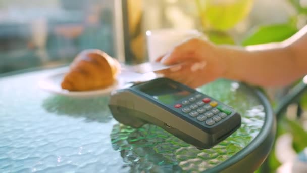 NFC pago con tarjeta de crédito. Mujer pagando con tarjeta de crédito sin contacto con tecnología NFC para pagar la orden en la terminal bancaria en un café. Transacción inalámbrica de dinero. Pago inalámbrico — Vídeo de stock