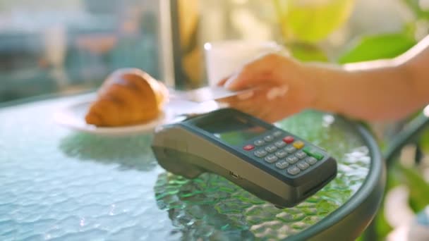 NFC credit card payment. Woman paying with contactless credit card with NFC technology to pay order on bank terminal in a cafe. Wireless money transaction. Wireless payment — Stockvideo