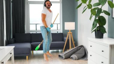 Adam evi temizliyor ve süpürgeyle dans ediyor. Yavaş çekim