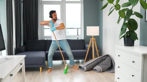 Uomo che pulisce la casa e si diverte a ballare con una scopa — Video Stock