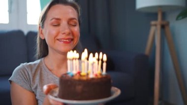 Mutlu, heyecanlı bir kadın Noel pastasına mum üflüyor, doğum gününü evde kutluyor, ağır çekimde.