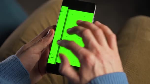 Man använder smartphone med grön mock-up skärm i vertikalt läge. Man surfar på Internet, tittar på innehåll, videor. — Stockvideo