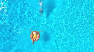 Kız donut havuzunda yüzerken adamın hava manzarası havuza dalıyor.