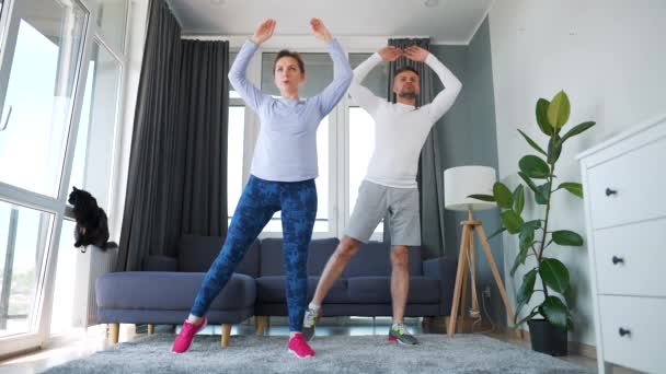 Кавказская пара делает кардио-упражнения дома в уютном светлом помещении, замедленной съемки. — стоковое видео