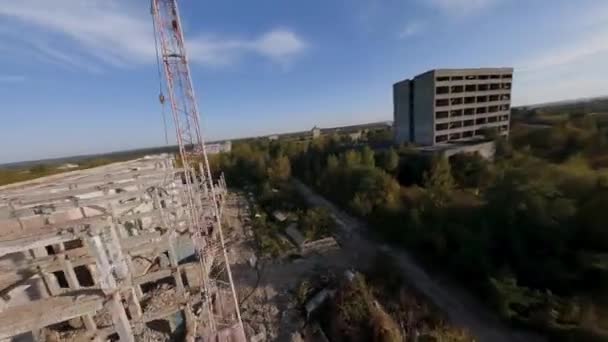 Drona FPV zboară rapid și manevrabil printre clădirile industriale abandonate și în jurul unui excavator . — Videoclip de stoc