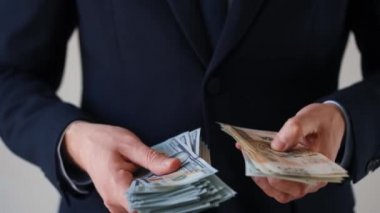 Resmi olarak giyinmiş bir adam Amerikan doları ve Polonya zloti banknotlarını tutuyor ve karşılaştırıyor. Yatırım, başarı, finansal beklentiler veya kariyer ilerlemesi kavramı
