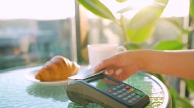 NFC kredi kartı ödemesi. NFC teknolojisiyle bağlantısız kredi kartıyla ödeme yapan bir kadın bir kafedeki banka terminalinden sipariş veriyor. Kablosuz para transferi. Kablosuz ödeme