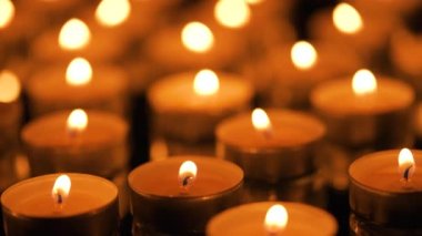 Siyah arkaplanda yanan çok sayıda küçük mum