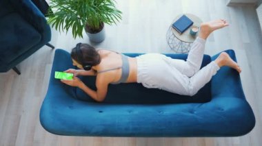 Kablosuz kulaklık takan, müzik dinleyen, mobil uygulamalar kullanan ya da sosyal ağlarda akıllı telefondan iletişim kuran yeşil model ekranlı bir kadın.
