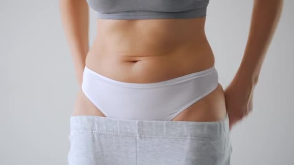 Woman puts on her pants, strokes her stomach and gives a thumbs up. Concept of healthy digestion and bowel function. — Stock Video