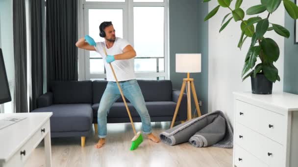 Adam evi temizliyor ve süpürgeyle dans ediyor. Yavaş çekim — Stok video