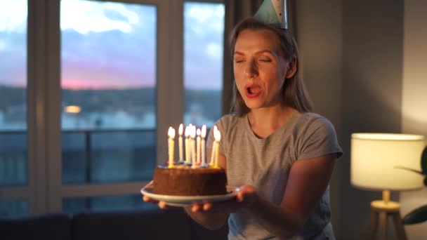 Feliz mulher animada fazendo desejo estimado e soprando velas no bolo de férias, celebrando aniversário em casa, câmera lenta — Vídeo de Stock