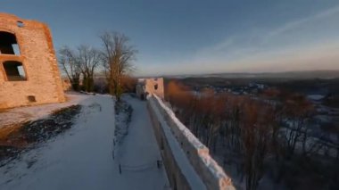 Kışın gün batımında tepedeki güzel tarihi şatonun havadan görünüşü harabeye döner. Tenczyn Kalesi, Polonya. FPV insansız hava aracı ile çekildi.