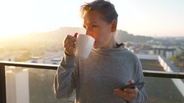 Kadın güne bir fincan çay ya da kahveyle başlıyor ve şafak vakti balkondaki akıllı telefonundaki e-postaları kontrol ediyor..