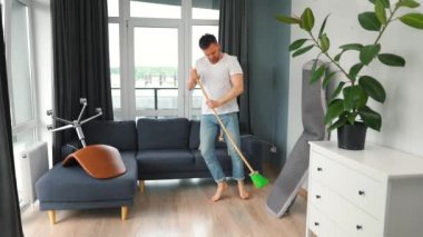 Adam evi temizliyor ve süpürgeyle dans ediyor. Yavaş çekim