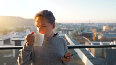 Kadın güne bir fincan çay ya da kahveyle başlıyor ve şafak vakti balkondaki akıllı telefonundaki e-postaları kontrol ediyor..