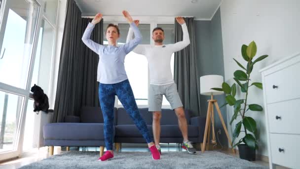 Καυκάσιο ζευγάρι κάνει άσκηση στο σπίτι σε άνετο φωτεινό δωμάτιο, αργή κίνηση. — Αρχείο Βίντεο
