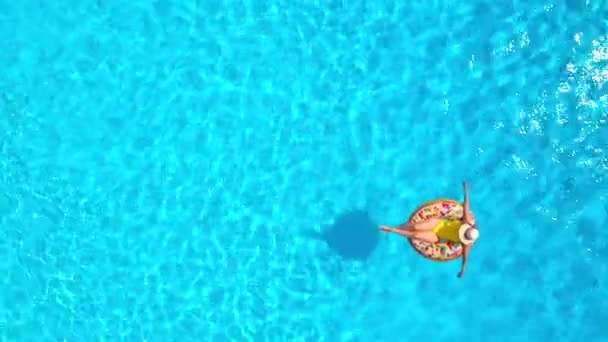 プールでドーナツに横たわって黄色の水着の女性の空中ビュー — ストック動画