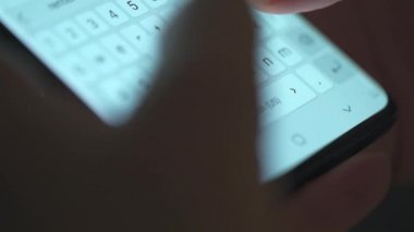 Akıllı telefondan yazı yazan bir kadın eli. Yakın plan. Akşamları akıllı telefonları kullanarak.