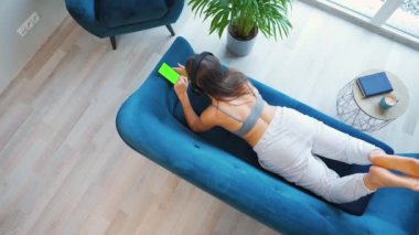 Kablosuz kulaklık takan, müzik dinleyen, mobil uygulamalar kullanan ya da sosyal ağlarda akıllı telefondan iletişim kuran yeşil model ekranlı bir kadın.