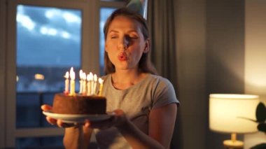 Mutlu, heyecanlı bir kadın Noel pastasına mum üflüyor, doğum gününü evde kutluyor, ağır çekimde.