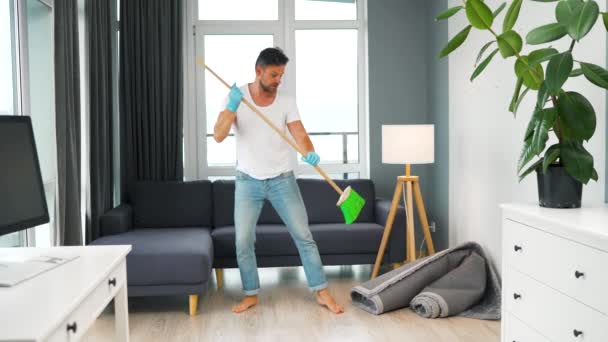 Un uomo che pulisce la casa e si diverte a ballare con una scopa. Rallentatore — Video Stock