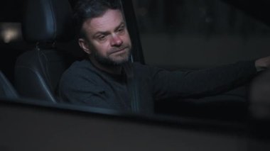 Adam arabada oturuyor, trafik kurallarını ihlal ettiği için polis tarafından durdurulduğu için üzgün.