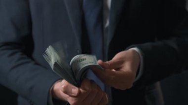 Resmi olarak giyinmiş adam Amerikan dolarlarını sayıyor. Yatırım, başarı, finansal beklentiler veya kariyer ilerlemesi kavramı