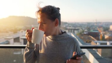 Kadın güne bir fincan çay ya da kahveyle başlıyor ve şafak vakti balkondaki akıllı telefonundaki e-postaları kontrol ediyor..