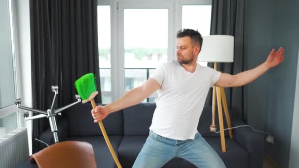 Facet sprząta dom i dobrze się bawi tańcząc z miotłą. Zwolniony ruch — Wideo stockowe