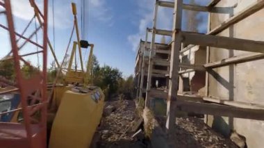 FPV insansız hava aracı, terk edilmiş sanayi binaları ve bir kazıcının etrafında hızla ve manevra kabiliyetiyle uçar..