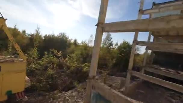 Le drone FPV vole rapidement et manœuvrable parmi les bâtiments industriels abandonnés et autour d'une pelle. — Video