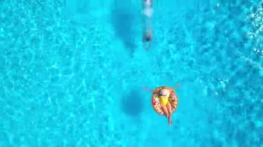 Kız donut havuzunda yüzerken adamın hava manzarası havuza dalıyor.