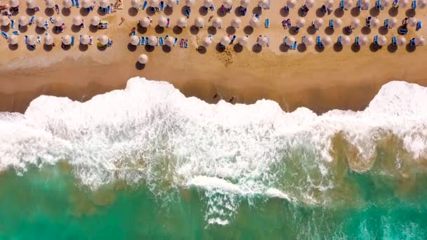 Aerial view of the sea, sandy beach, sun umbrellas and sunbeds, unrecognizable people. Beautiful vacation and tourism destination in Crete, Greece. — Stock Video
