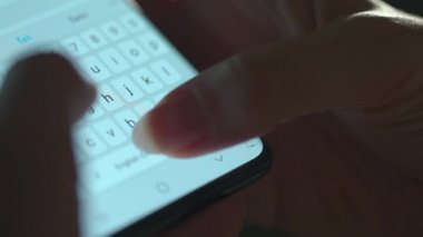 Akıllı telefondan yazı yazan bir kadın eli. Yakın plan. Akşamları akıllı telefonları kullanarak.