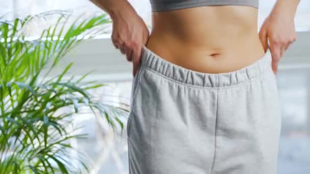 Una donna si mette i pantaloni, si accarezza lo stomaco e dà un pollice in su. Concetto di sana digestione e funzione intestinale. — Video Stock