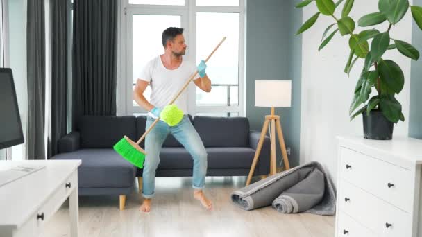 男は家を掃除し、ほうきと洗濯で楽しいダンスをしています。スローモーション — ストック動画