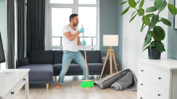 Mężczyzna sprzątanie domu i zabawy taniec z miotłą — Wideo stockowe