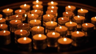 Siyah arkaplanda yanan çok sayıda küçük mum