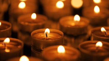 Siyah arkaplanda yanan çok sayıda küçük mum