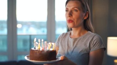 Mutlu, heyecanlı bir kadın Noel pastasına mum üflüyor, doğum gününü evde kutluyor, ağır çekimde.