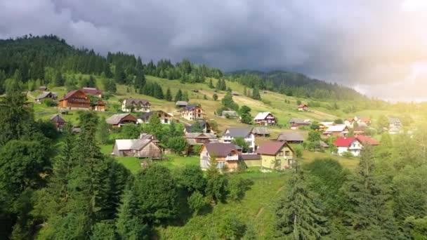 Voo sobre uma aldeia de montanha entre a floresta de coníferas. Névoa sobe sobre as encostas da montanha — Vídeo de Stock