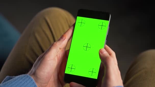 Uomo che utilizza smartphone con schermo mock-up verde in modalità verticale. Uomo che naviga in Internet, guarda contenuti, video. — Video Stock