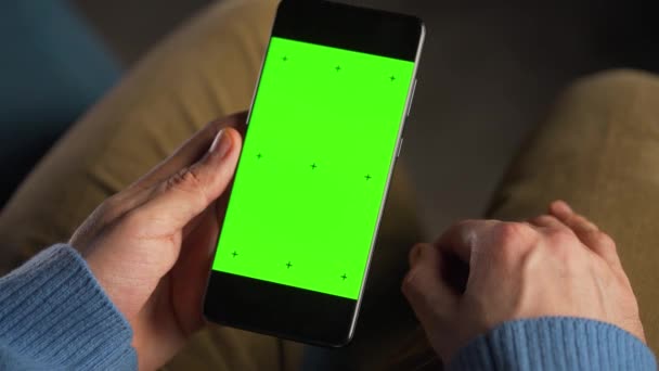 Mann benutzt Smartphone mit grünem Bildschirm-Attrappe im vertikalen Modus. Mann surft im Internet, schaut Inhalte, Videos. — Stockvideo