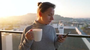 Kadın güne bir fincan çay ya da kahveyle başlıyor ve şafak vakti balkondaki akıllı telefonundaki e-postaları kontrol ediyor..
