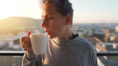 Kadın güne bir fincan çay ya da kahveyle başlıyor ve şafak vakti balkondaki akıllı telefonundaki e-postaları kontrol ediyor..